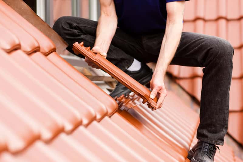 Handwerker deckt ein Dach mit neuen Ziegeln ein